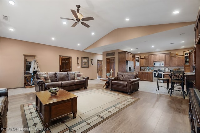 living room featuring ceiling fan, vaulted ceiling, and light wood-type flooring