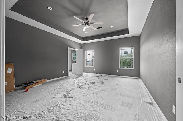 unfurnished room with a raised ceiling and ceiling fan