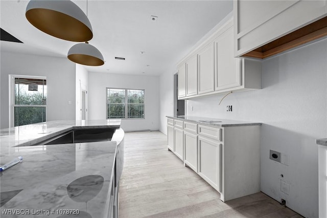 kitchen with white cabinetry, light stone countertops, and light hardwood / wood-style flooring