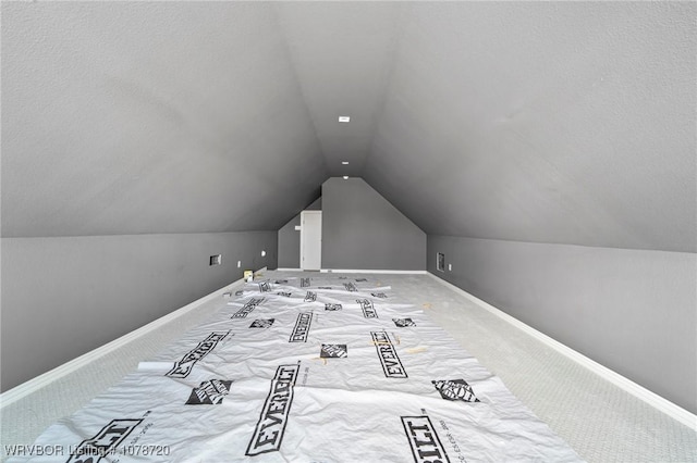 unfurnished bedroom featuring vaulted ceiling, a textured ceiling, and carpet