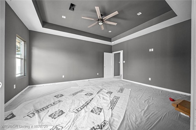 unfurnished room with ceiling fan, carpet flooring, and a raised ceiling