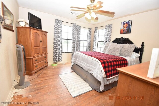 bedroom with multiple windows, ceiling fan, and wood-type flooring