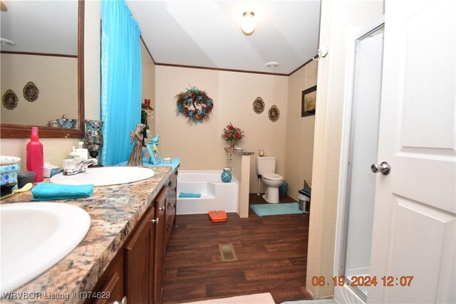 bathroom featuring vanity, crown molding, hardwood / wood-style flooring, toilet, and a tub