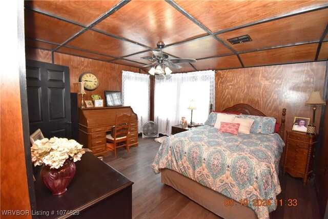 bedroom with ceiling fan, dark wood-type flooring, and wooden walls