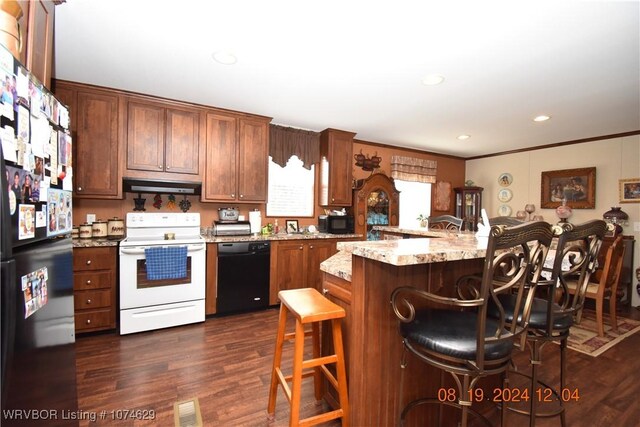 kitchen with light stone countertops, dark hardwood / wood-style flooring, a breakfast bar, crown molding, and black appliances