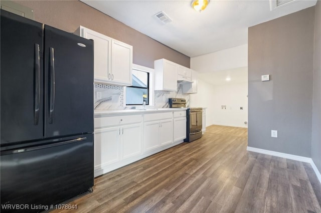 411 N Logan St, Charleston, AR 72933 - kitchen with stainless steel electric stove, tasteful backsplash, white cabinetry, hardwood / wood-style flooring, and black fridge