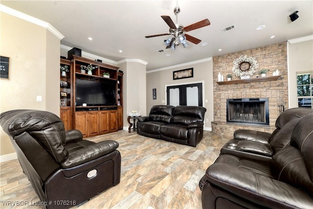 living room featuring ceiling fan, a stone fireplace, and crown molding