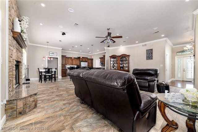 living room featuring a fireplace, ceiling fan with notable chandelier, and crown molding