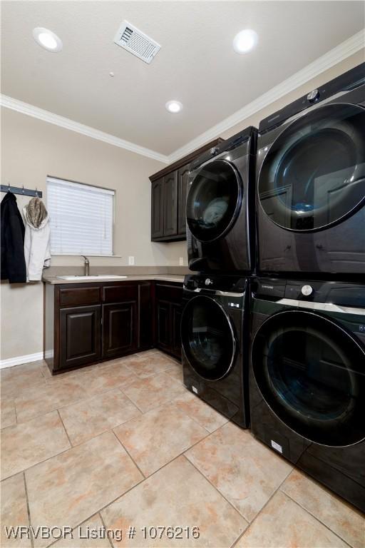 laundry room with stacked washer / drying machine, cabinets, sink, and crown molding