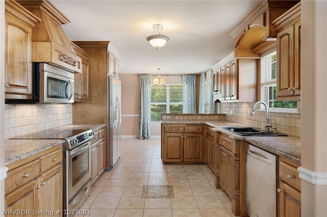 kitchen featuring appliances with stainless steel finishes, backsplash, sink, light tile patterned floors, and hanging light fixtures