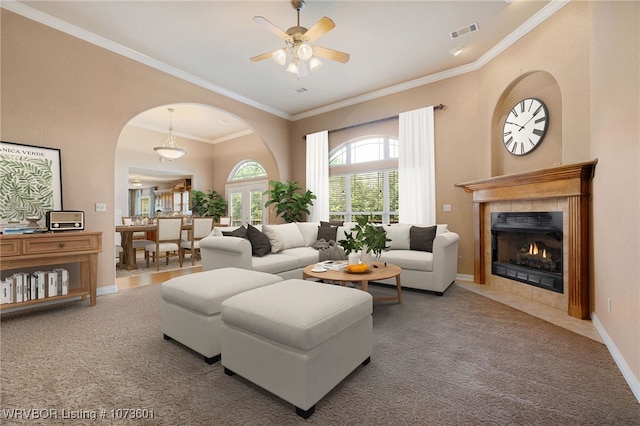 living room with carpet flooring, ceiling fan, a fireplace, and ornamental molding