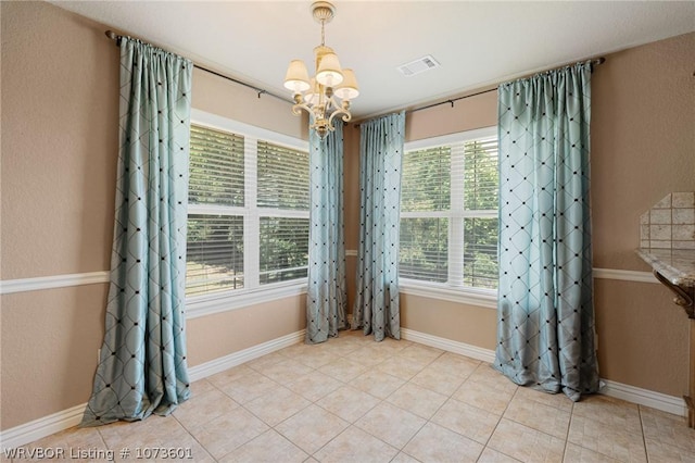 tiled empty room with a healthy amount of sunlight and a chandelier