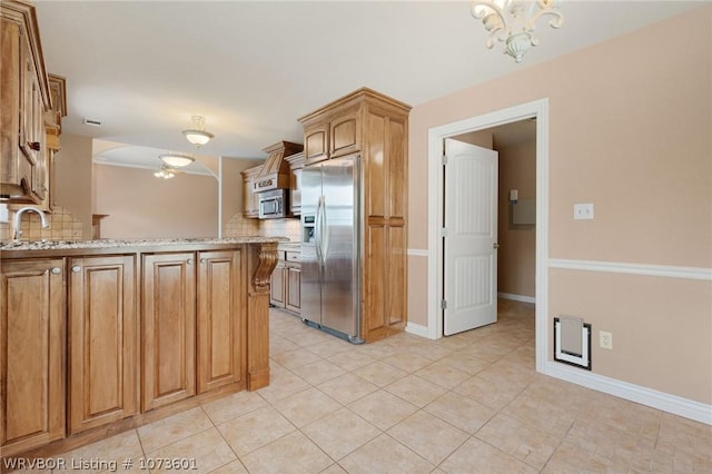 kitchen featuring an inviting chandelier, decorative backsplash, light tile patterned floors, light stone countertops, and appliances with stainless steel finishes