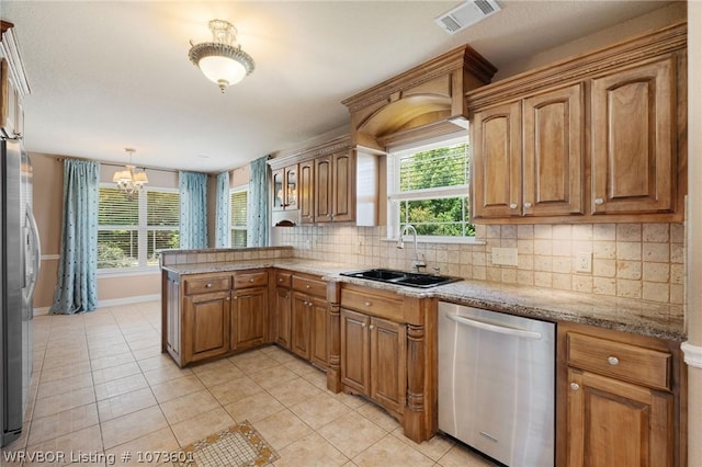 kitchen featuring kitchen peninsula, appliances with stainless steel finishes, sink, decorative light fixtures, and a chandelier