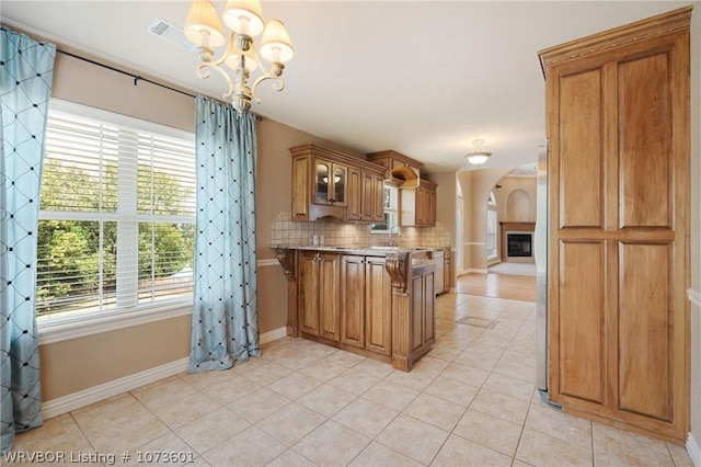 kitchen with a healthy amount of sunlight, light tile patterned flooring, hanging light fixtures, and a notable chandelier