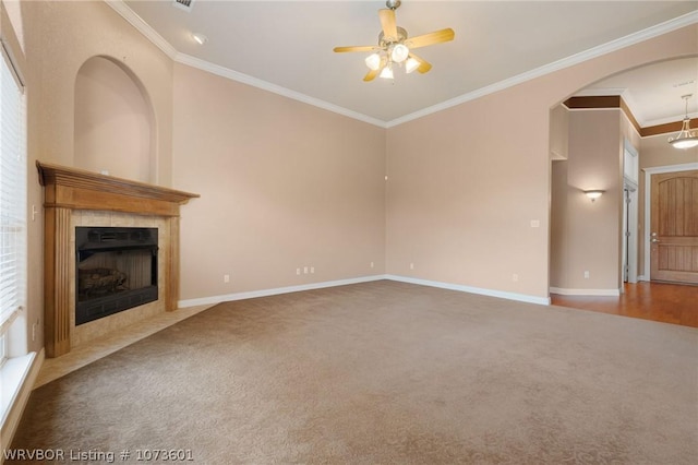 unfurnished living room featuring a tile fireplace, ceiling fan, carpet, and ornamental molding