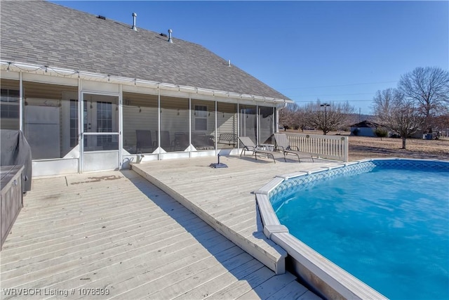 view of pool with a sunroom and a deck