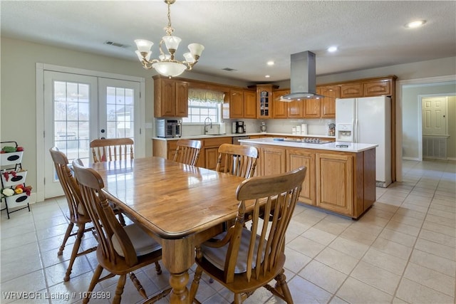 dining area with sink, a chandelier, light tile patterned floors, a textured ceiling, and french doors