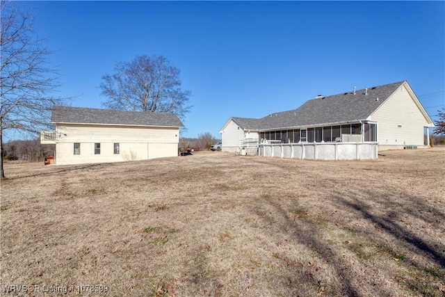 rear view of property featuring a yard and a sunroom