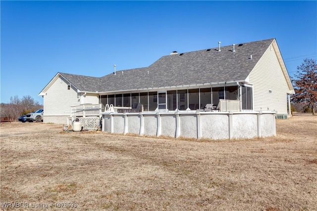 back of property featuring a sunroom and a lawn