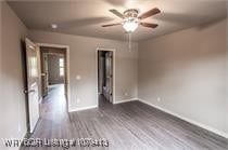 unfurnished bedroom featuring a ceiling fan, baseboards, and wood finished floors