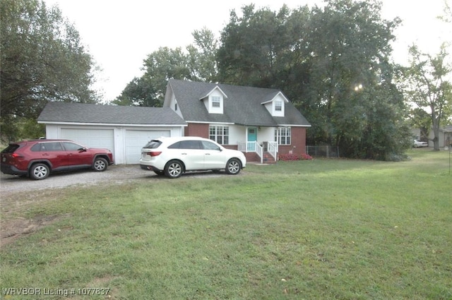 cape cod house featuring a garage and a front lawn