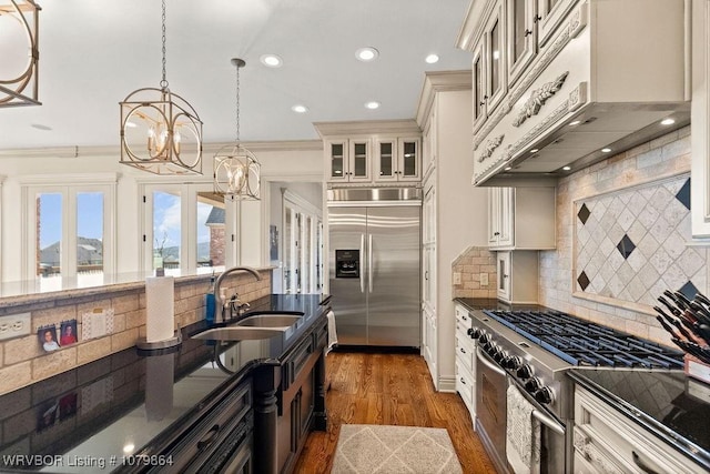 kitchen with an inviting chandelier, under cabinet range hood, a sink, dark wood-style floors, and appliances with stainless steel finishes
