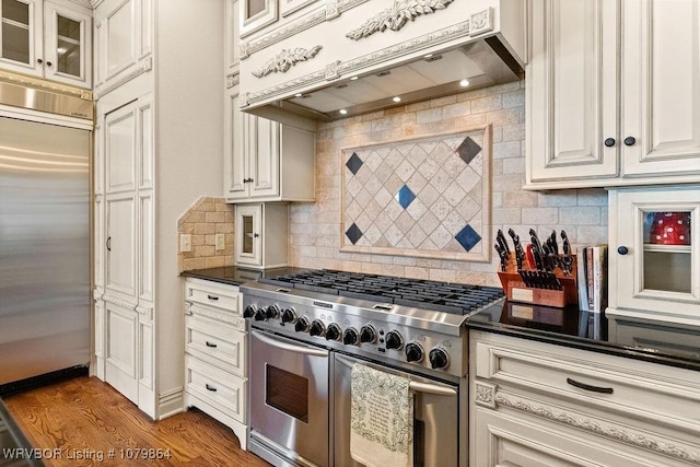 kitchen with high end appliances, glass insert cabinets, backsplash, and premium range hood
