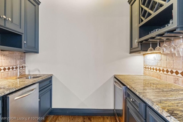 kitchen featuring open shelves, baseboards, light stone counters, dishwasher, and wood finished floors