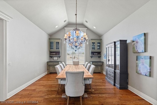 dining area with vaulted ceiling, wood finished floors, baseboards, visible vents, and an inviting chandelier