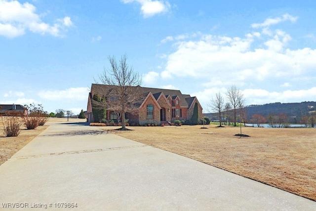 view of front of home featuring concrete driveway, a water view, and a front lawn