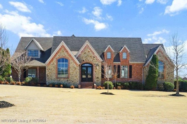 view of front of home featuring brick siding, a front lawn, and french doors