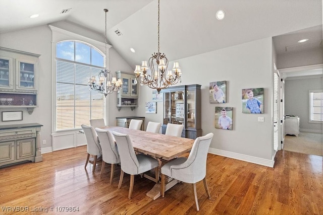 dining space with a healthy amount of sunlight, light wood-style flooring, and an inviting chandelier