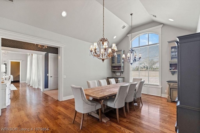 dining space with visible vents, wood finished floors, lofted ceiling, and a chandelier