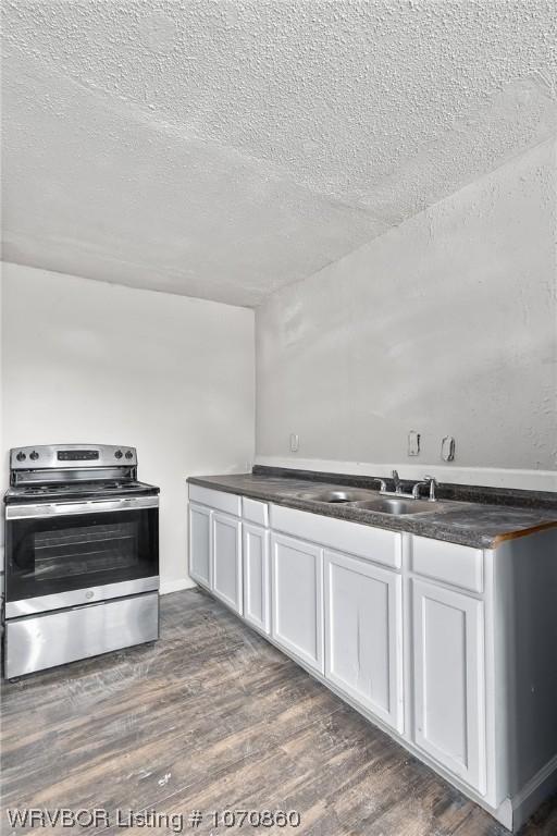 kitchen with dark hardwood / wood-style floors, white cabinetry, stainless steel range with electric cooktop, and sink