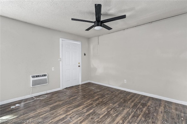 spare room with heating unit, ceiling fan, dark wood-type flooring, and a textured ceiling