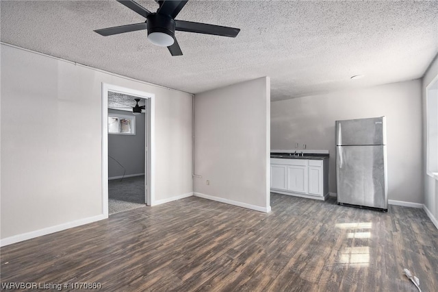 unfurnished living room featuring a textured ceiling, ceiling fan, sink, and dark wood-type flooring