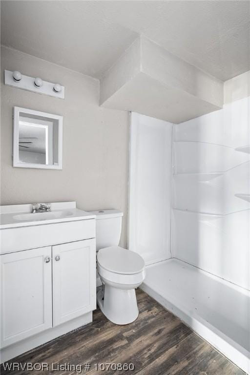 bathroom with toilet, vanity, wood-type flooring, and walk in shower