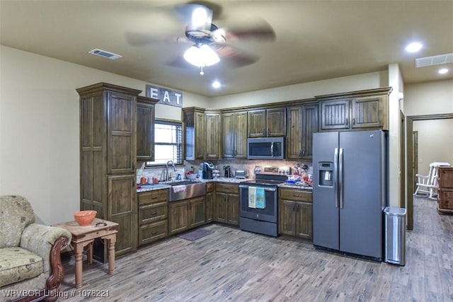 kitchen featuring backsplash, stainless steel appliances, light hardwood / wood-style flooring, and sink