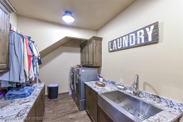 laundry room featuring washer and clothes dryer, cabinets, light wood-type flooring, and sink