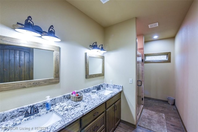 bathroom with hardwood / wood-style flooring, vanity, and a shower with door