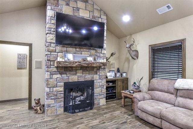 living room featuring a fireplace, vaulted ceiling, and hardwood / wood-style flooring