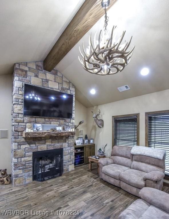 living room with a chandelier, vaulted ceiling with beams, hardwood / wood-style flooring, and a stone fireplace