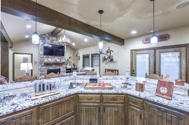 kitchen featuring vaulted ceiling with beams, light stone countertops, a fireplace, and pendant lighting