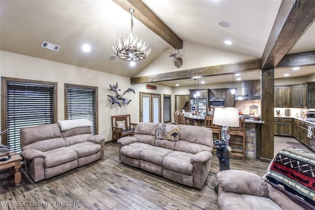 living room with vaulted ceiling with beams, light wood-type flooring, and a notable chandelier