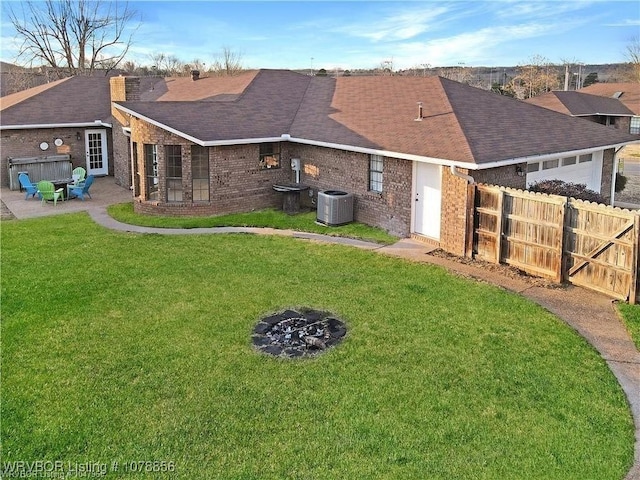 rear view of property with a yard, central AC unit, an outdoor fire pit, and a patio area