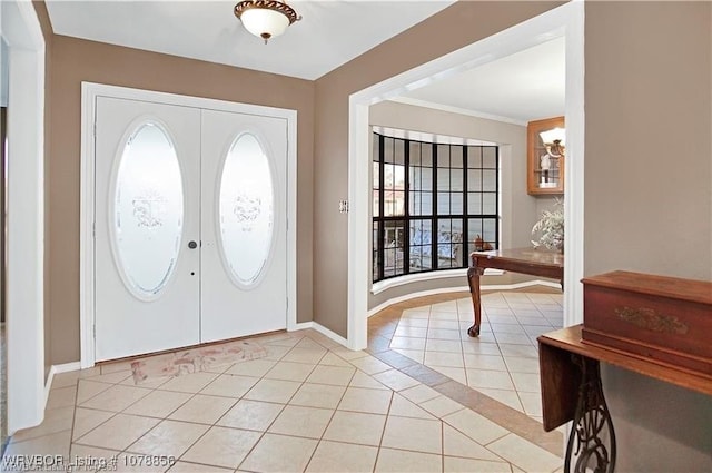 entryway featuring light tile patterned floors, crown molding, and french doors