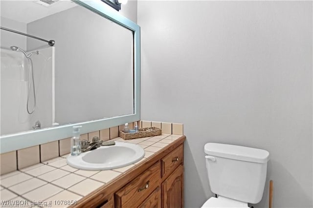 bathroom featuring vanity, a shower, and toilet