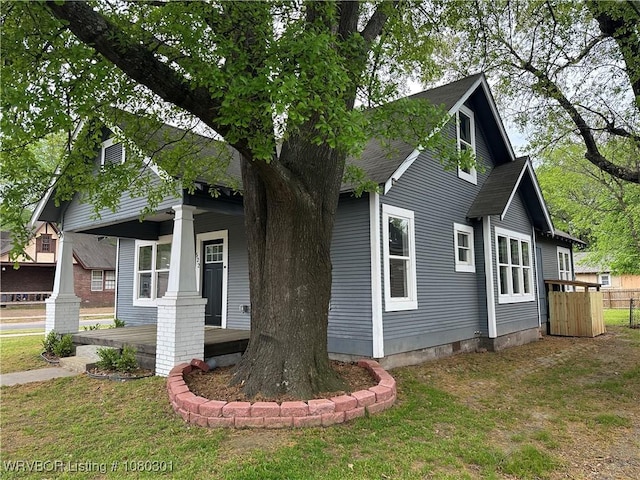 view of front facade featuring fence, a shingled roof, covered porch, and a front yard