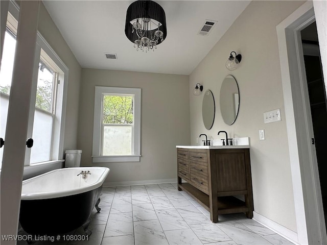 bathroom with a freestanding bath, visible vents, and marble finish floor